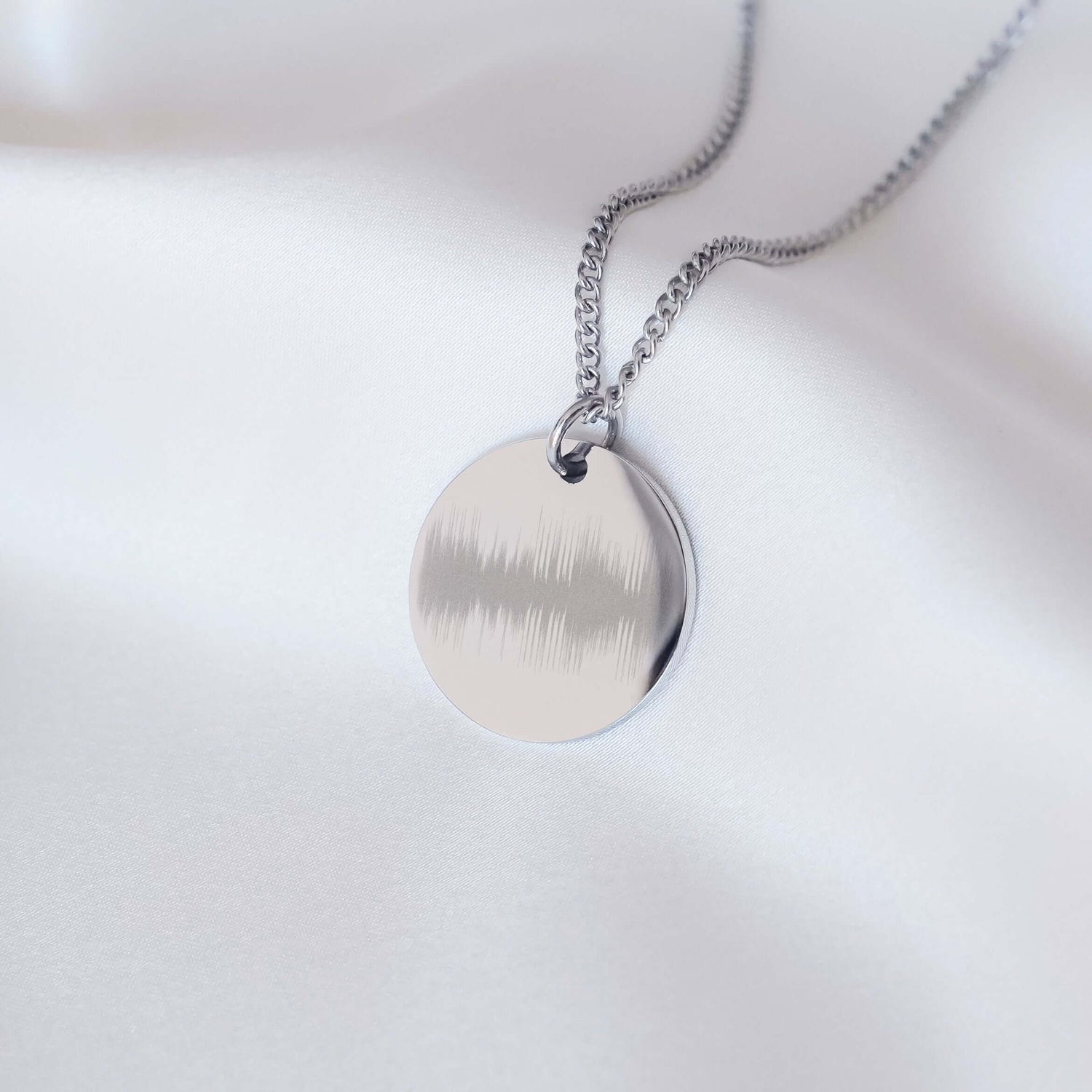 Disc shaped necklace engraved with a soundwave