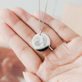 Disc shaped pendant engraved with a babies hand and footprint